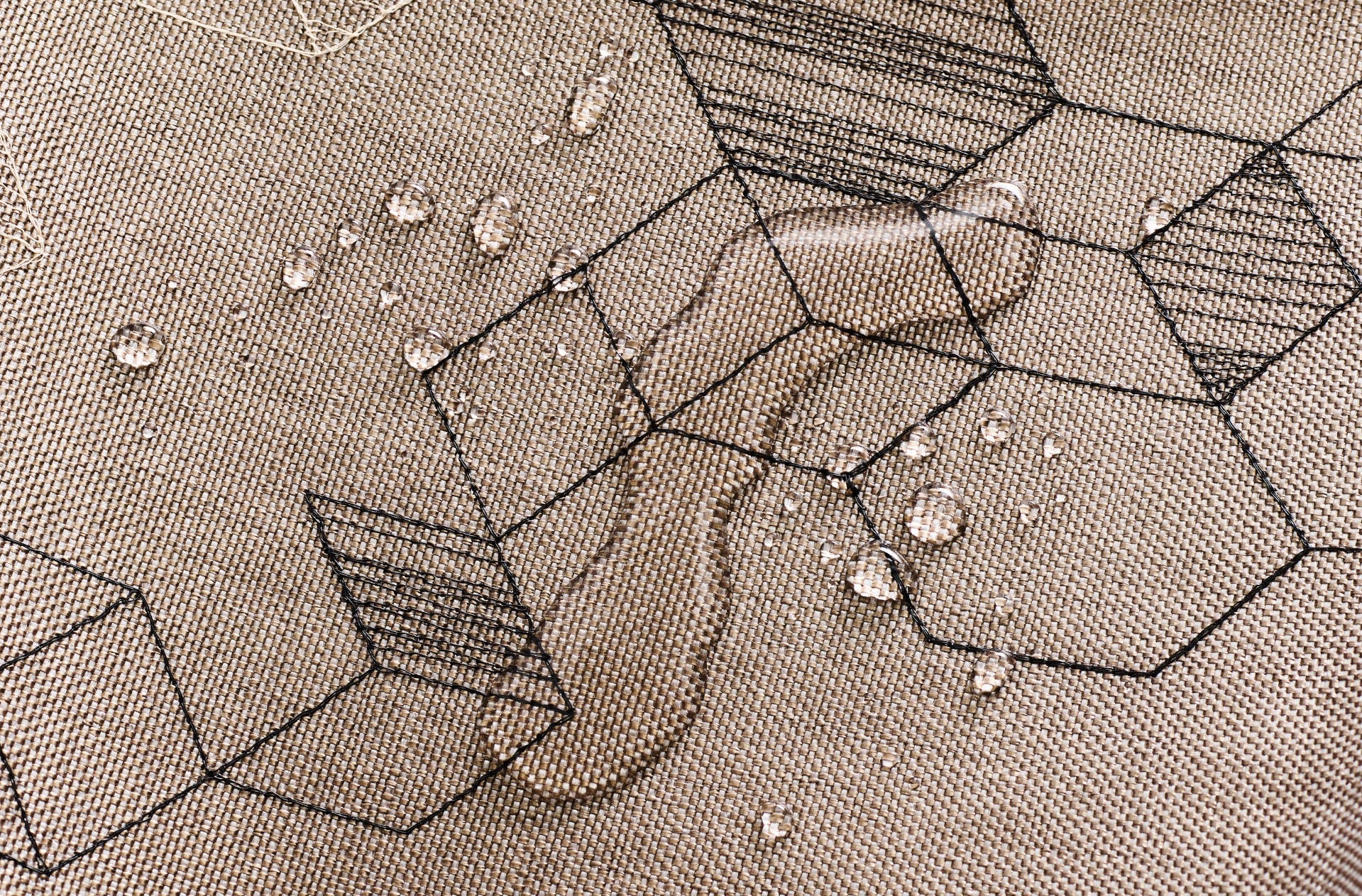 Close-up of Xorel woven textile with a geometric pattern and water beading on its surface